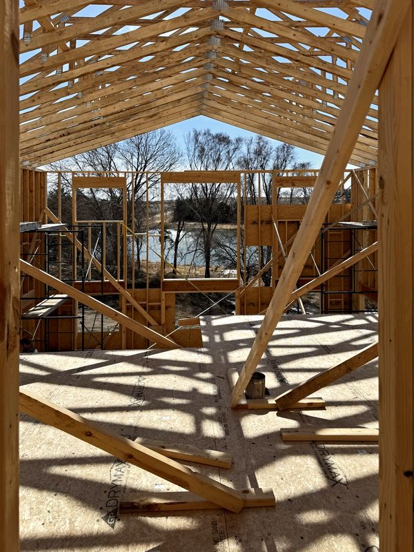 Looking through new roof trusses and wall framing toward a pond